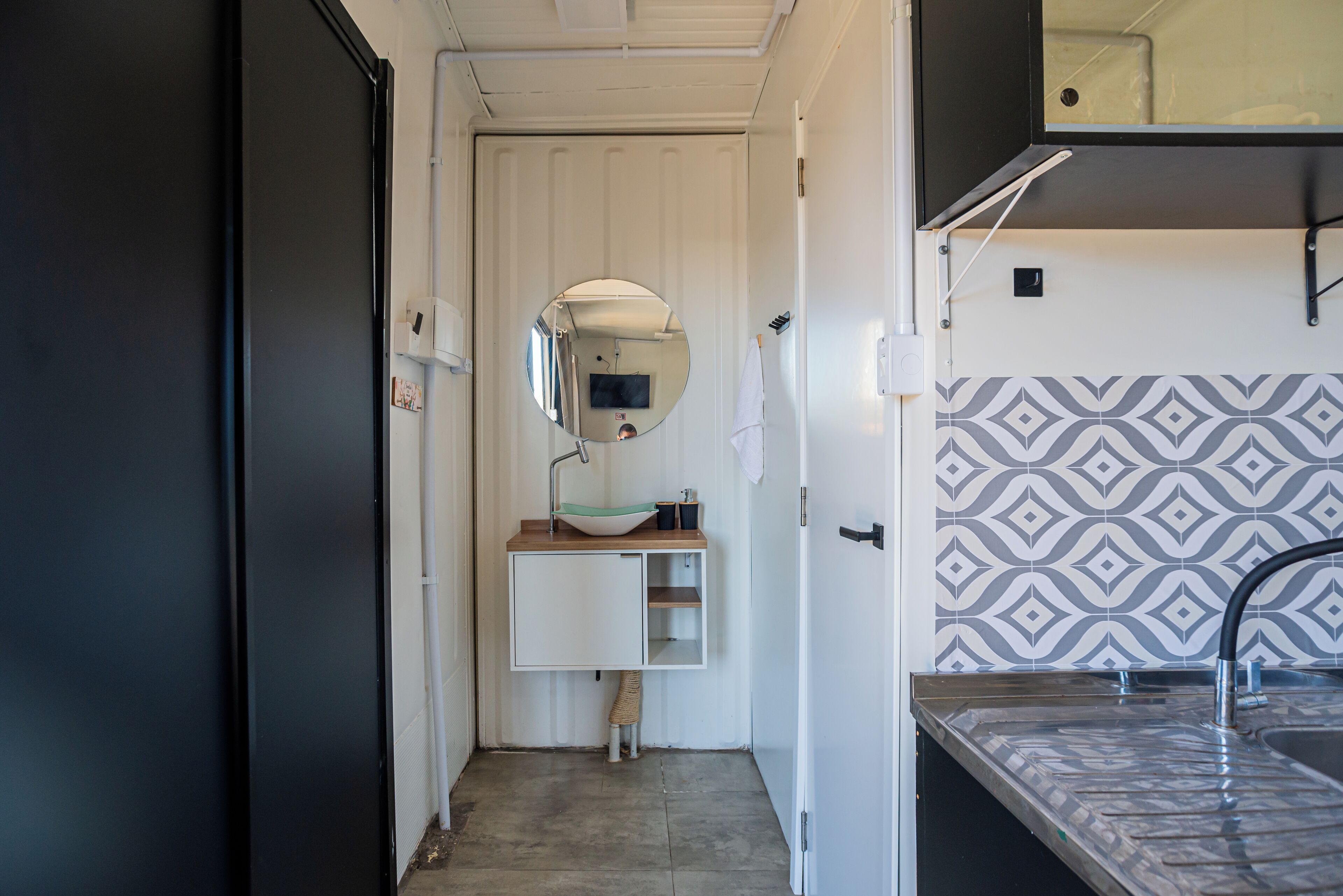 A compact bathroom with a white sink, mirror, and patterned wall tiles.