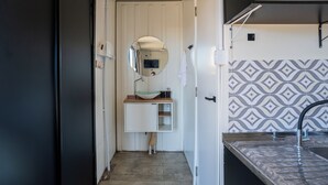 Ein kleines Badezimmer mit einem weißen Waschbecken, Spiegel und Wandfliesen mit Muster.