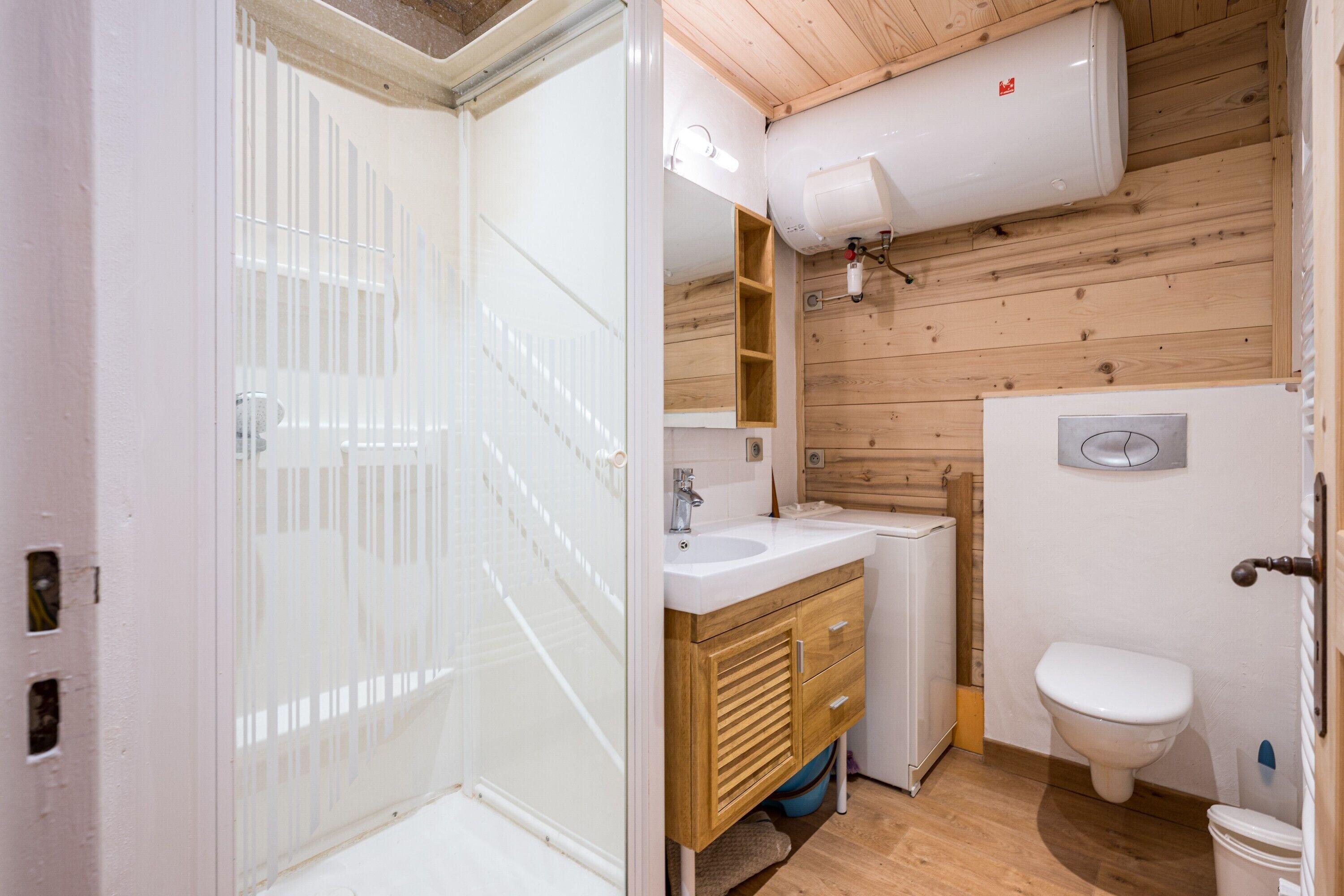 Ein Badezimmer mit Dusche, Waschbecken, Toilette und Holzwänden.
