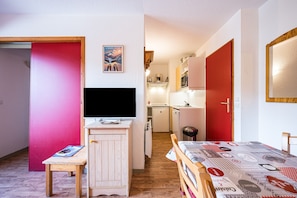 A room with a bed, a desk, a television, and a kitchenette.