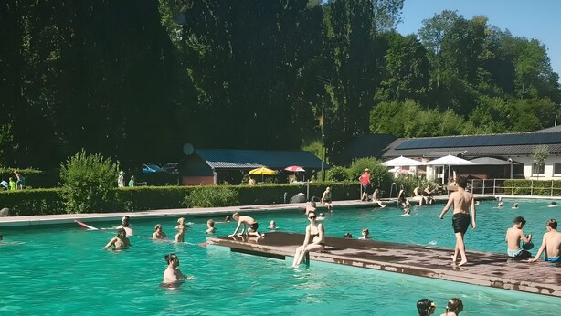 A swimming pool with people swimming and playing, surrounded by greenery and buildings. - 'Bilstein' Apartment in a Quiet, Central Location (Lennestadt)