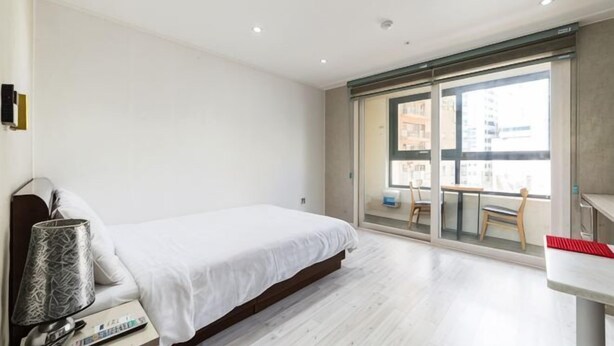 A bedroom with a bed, a desk, and a chair near a window. - Residence Hotel Lamia (Daejeon)