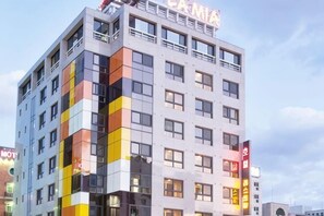 Ein mehrstöckiges Hotel mit modernem Design, erkennbar an einer großen 'CA'-Beschriftung auf dem Dach.
