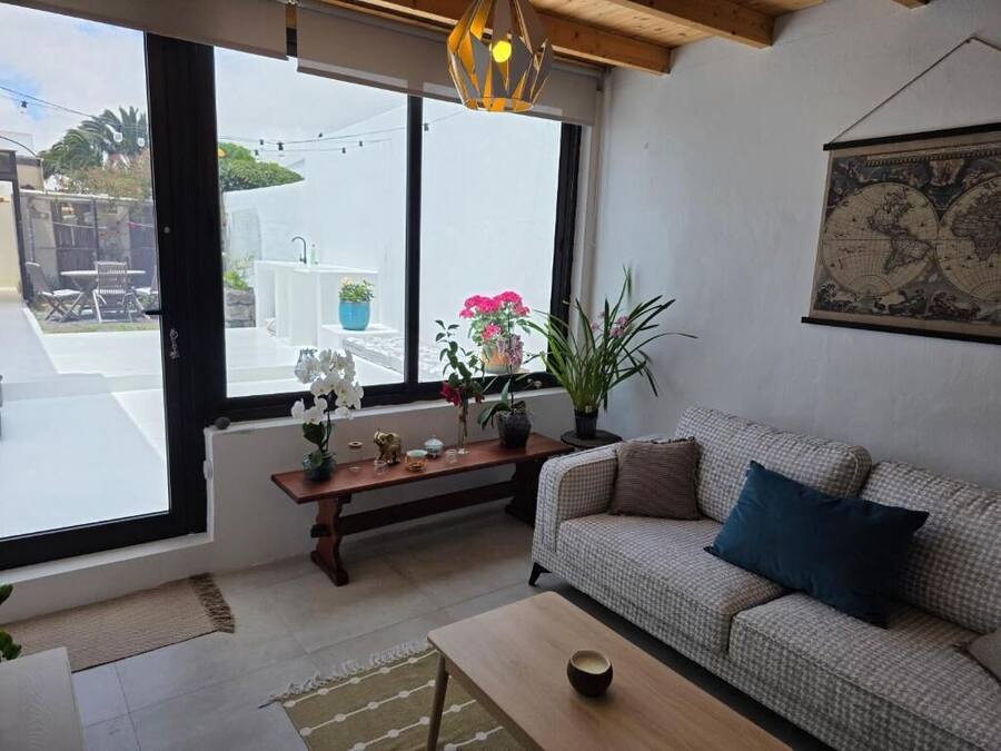 Una sala de estar con sofá, una mesa de centro, un banco de madera y un ventanal grande.