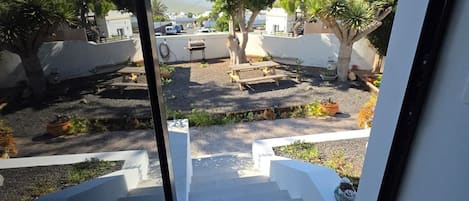 A staircase leading to a courtyard with a view of the sea, surrounded by potted plants and a white wall.