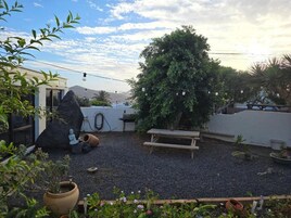 Un patio con un banco de madera, un árbol grande y una escultura de piedra.