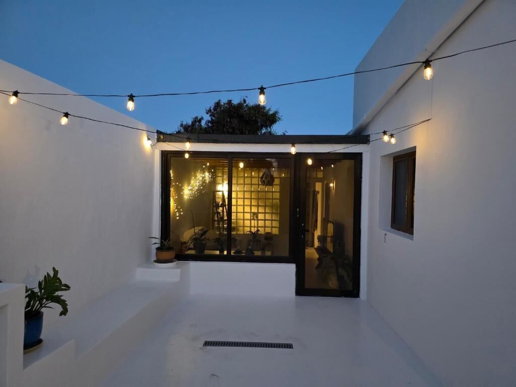 A modern building with a glass door entrance, potted plants, and string lights.