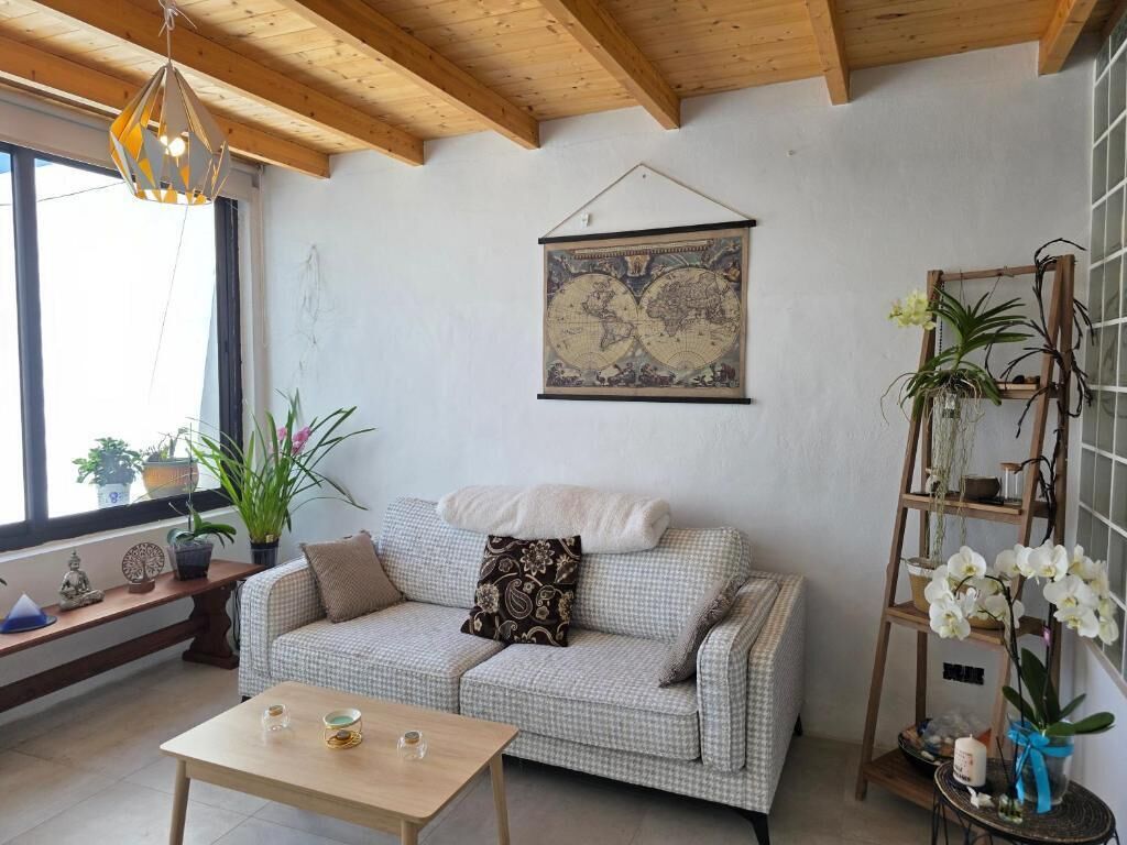 A cozy living room with a checkered sofa, a wooden coffee table, and a world map on the wall.