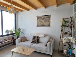 Un salon chaleureux avec un canapé à carreaux, une table basse en bois et une carte du monde accrochée au mur.