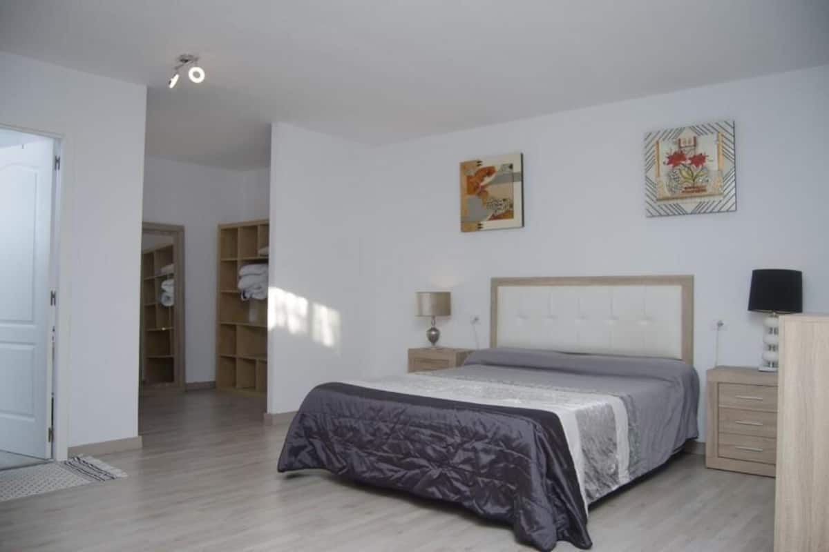 Une chambre à coucher avec un lit, des tables de chevet, une armoire et une porte.