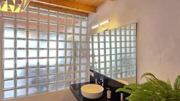 Un baño con un ventanal grande, un lavamanos y un espejo.