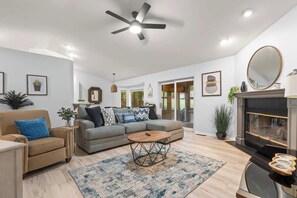 Una sala de estar con sofá, sillón, mesa de centro y chimenea.