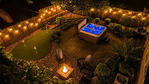 A backyard with a hot tub, seating area, and a small putting green.