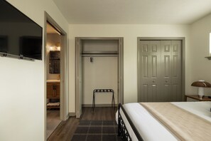A bedroom with a bed, a nightstand, a lamp, a closet, and a television. - The Long Shot ~ NuLu, Mini Golf, Hot Tub, Fire Pit, BBQ (Louisville)