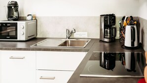 Eine Küche mit Mikrowelle, Kaffeemaschine, Toaster und Spüle.