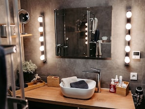 Un baño con tocador, espejo, luces y artículos de aseo.