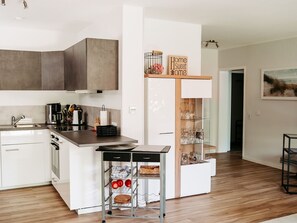 Cozinha moderna com ilha central, forno embutido e espaço para vinhos.