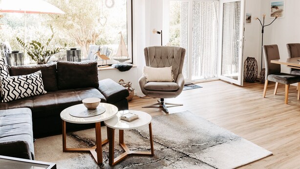 Ein modernes Wohnzimmer mit einer Couch, Sesseln, einem Couchtisch und einem Essbereich mit Stühlen.