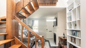 Un escalier menant à un espace de vie comprenant un canapé, une cheminée et une bibliothèque.