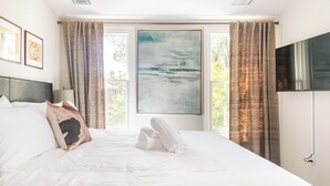 Une chambre d’hôtel avec un grand lit, un tableau au mur et un téléviseur fixé au mur.