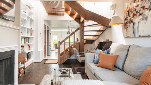Un salon moderne avec un escalier, une cheminée et une bibliothèque.