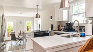 Une cuisine moderne avec des meubles blancs, des appareils en acier inoxydable et un grand îlot central.