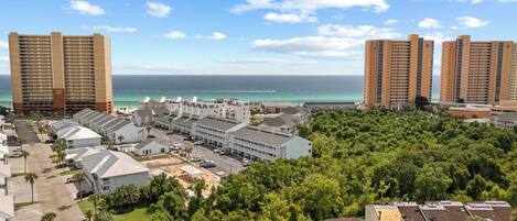 A coastal hotel area with multiple high-rise buildings, a parking lot, and lush greenery.