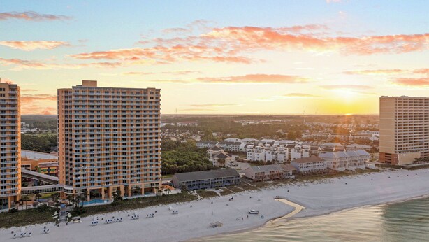 A beachfront hotel with multiple floors, a pool, and a beach area with sun loungers. - Gulf Walk by Avantstay West End Coastal Escape Renovated 1BR Condo Shared Pool & Beach Access (Panama City Beach)