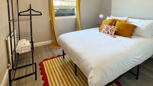 A bedroom with a bed, a hanging clothes rack, a window with curtains, and a floor lamp. - Playful 1 bed in Camden (Greater London)