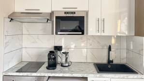 A modern kitchen with a built-in oven, a coffee maker, and a kettle. - Playful 1 bed in Camden (Greater London)