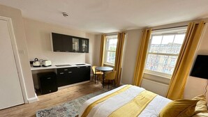 A hotel room with a bed, a desk, a chair, and a window. - Cozy studio Flat in Camden (Greater London)