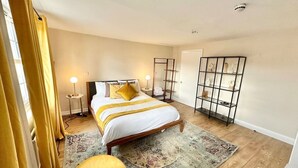 A bedroom with a bed, bedside tables, a nightstand, a mirror, a wardrobe, and a shelf with decorative items. - Cozy studio Flat in Camden (Greater London)