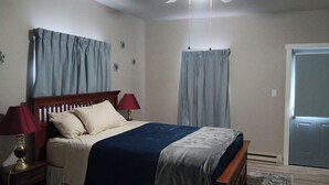Una camera da letto con un letto, due lampade da comodino, una ventola a soffitto e una porta.
