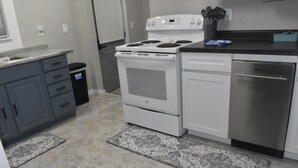 Cucina con piano cottura bianco, lavastoviglie e mobili grigi.