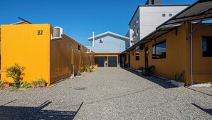 A building with a gravel driveway leading to a covered entrance. - Container 3 (Navegantes)