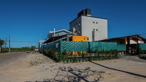 A building with a large, white structure and a smaller attached building with a green roof. - Container 3 (Navegantes)