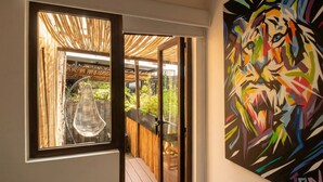 A room with a large window, a hanging chair, and a colorful abstract painting on the wall. - LA SELVA HOSTEL (Mexico City)