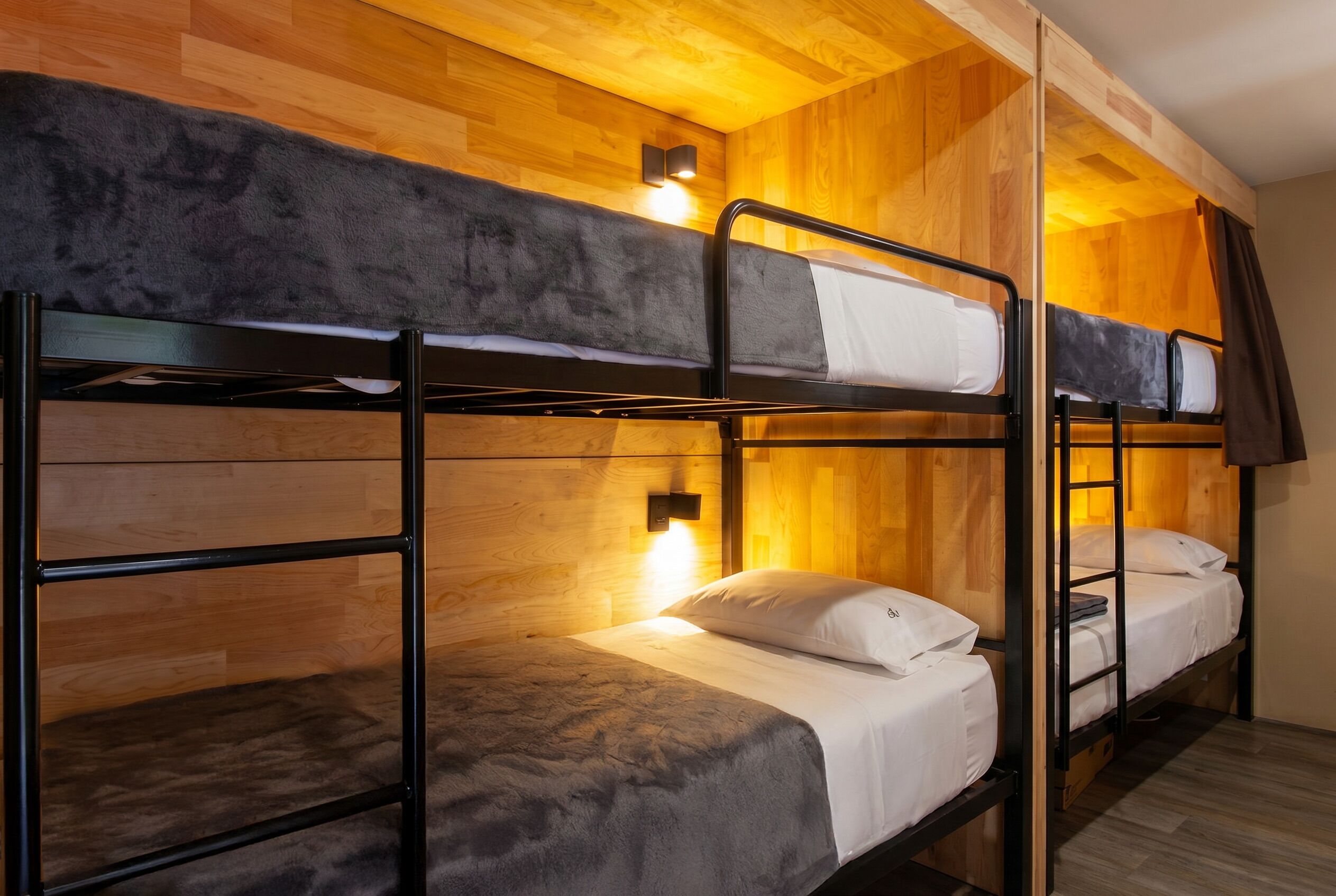 A bunk bed room with wooden walls and a single bedside lamp.