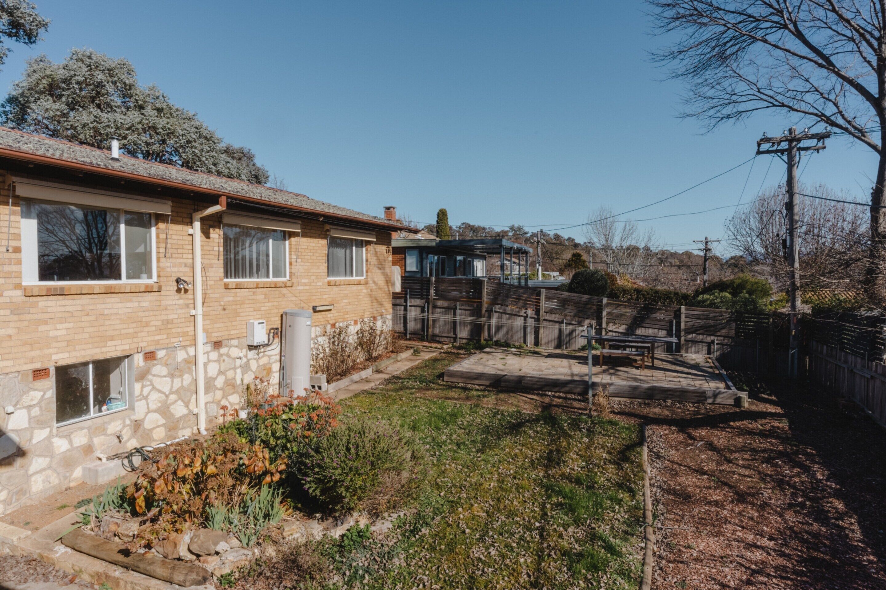 A residential property with a brick house, a covered outdoor seating area, and a fenced yard.