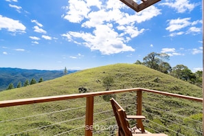 A wooden balcony railing overlooking a grassy hill with a clear sky. - Cabana c\ Jacuzzi prox. de Florianópolis VST026 (Anitapolis)
