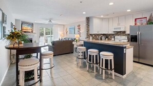 A modern kitchen with a central island, bar stools, and a refrigerator. - Lakeview Condo, Pools, Patio With Grill, Near PB2 Launch (Osage Beach)