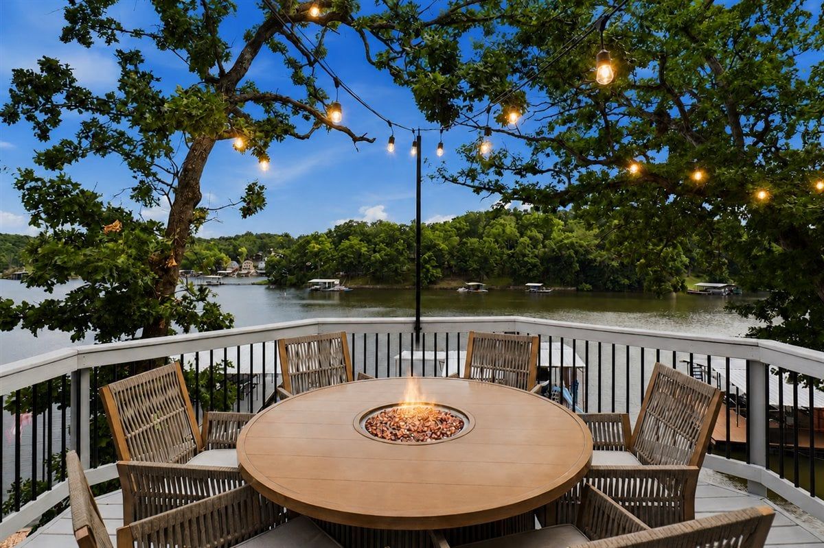An outdoor dining area with a round table and chairs, a fire pit, and string lights.