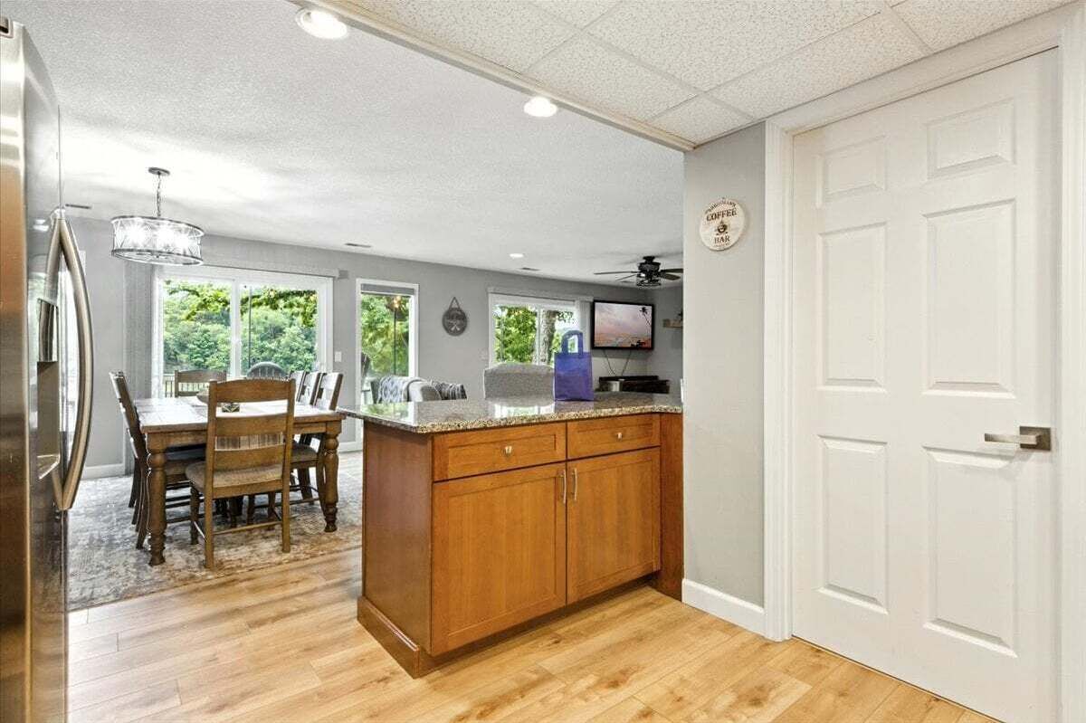 A kitchen with wooden cabinets, a granite countertop, and a dining area with a table and chairs.