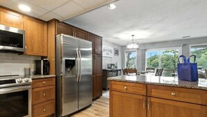 A modern kitchen with stainless steel appliances, wooden cabinets, and a large island with granite countertop.