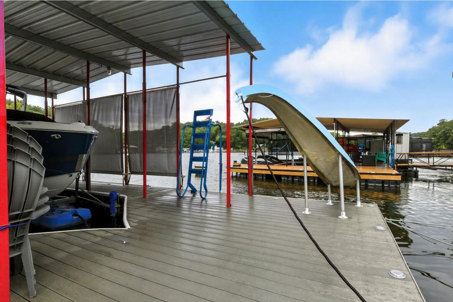 A covered boat dock with a boat, a ladder, and a covered seating area.