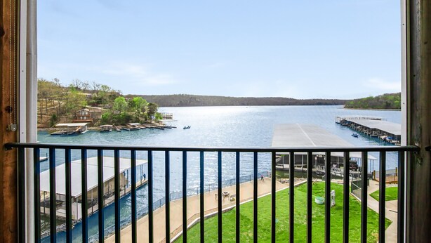 A view from a window overlooking a lake with docks, a grassy area, and a building with a roof.