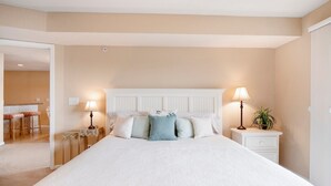 A bedroom with a large bed, two bedside tables with lamps, and a small table with a plant.