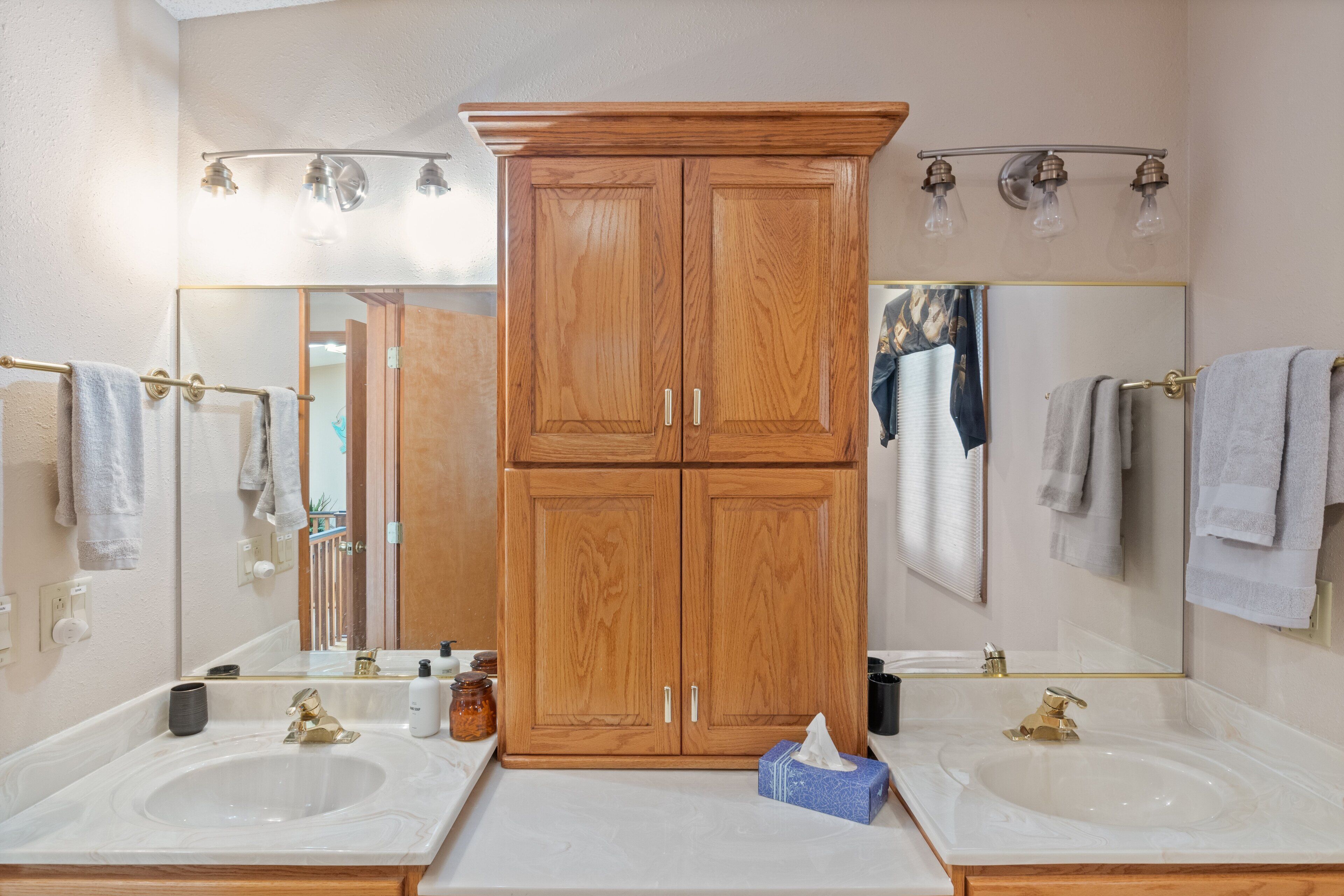 A bathroom with two sinks, wooden cabinets, and a large mirror.