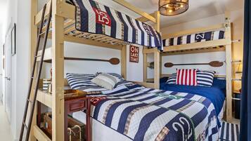 Une chambre avec un lit superposé, une literie à rayures, une échelle, un panneau indiquant « ON EST EN MODE VACANCES AU LAC » et une tête de lit en bois.