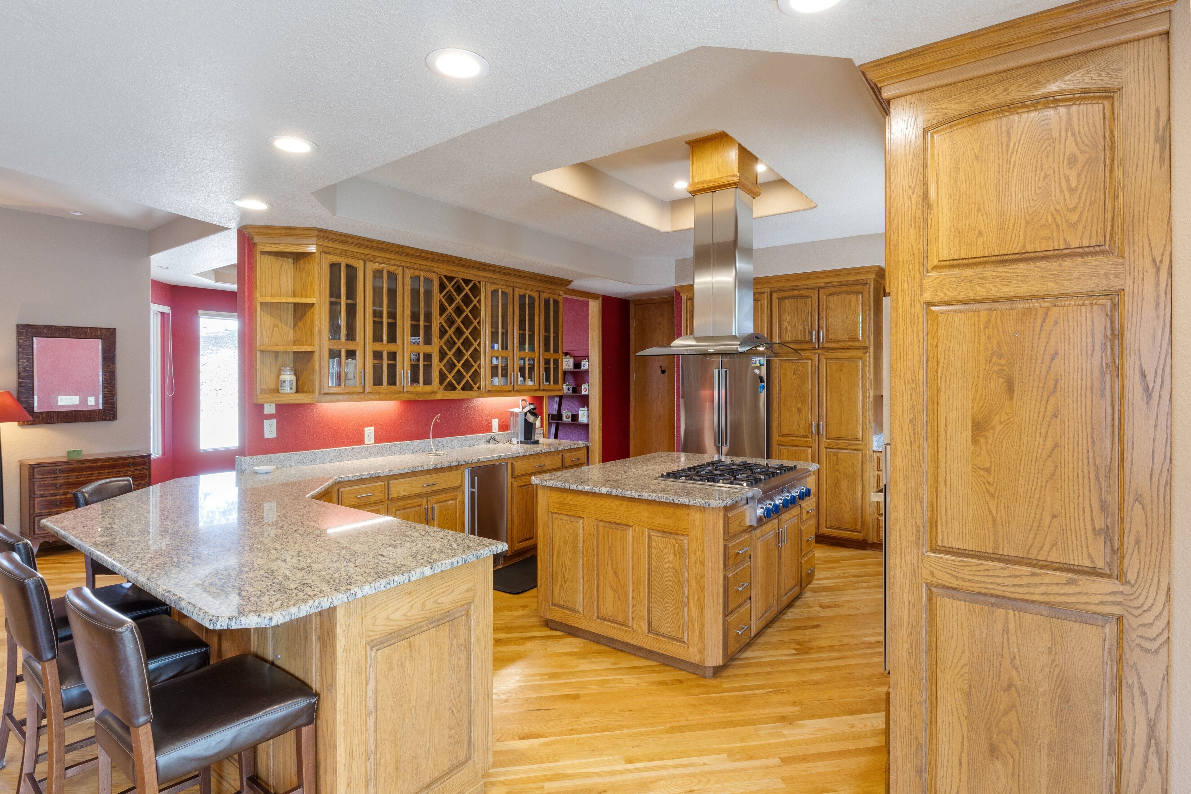 Une cuisine dotée de meubles en bois, de plans de travail en granit et d’une hotte aspirante en acier inoxydable.